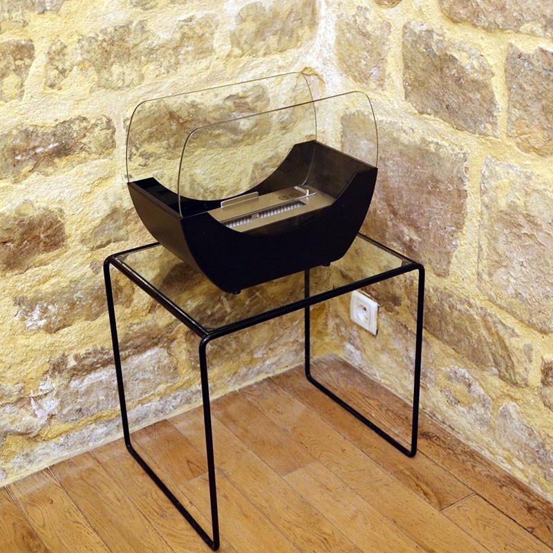 WIKAO Bioethanol Tischkamin CHLOE Tischfeuer in Schwarz mit Glas auf einem Metalltisch vor einer Steinwand