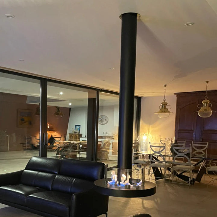 bioethanol-deckenkamin-haengekamin-decke-deckenmontage-ethanolkamin-rund-ativ-mit-glas-runder-brenner-mit-flammen-360-grad-flammenblick-in-modernen-wohnzimmer-neben-schwarzen-sofa