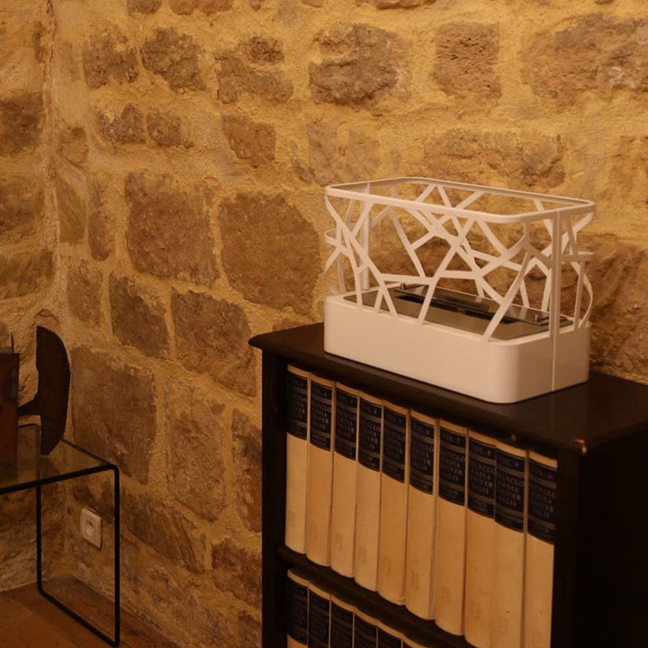 WIKAO Bioethanol Tischkamin ETNICA Tischfeuer in Weiß im verspielten Design auf einem schwarzen Regal vor einer Steinwand